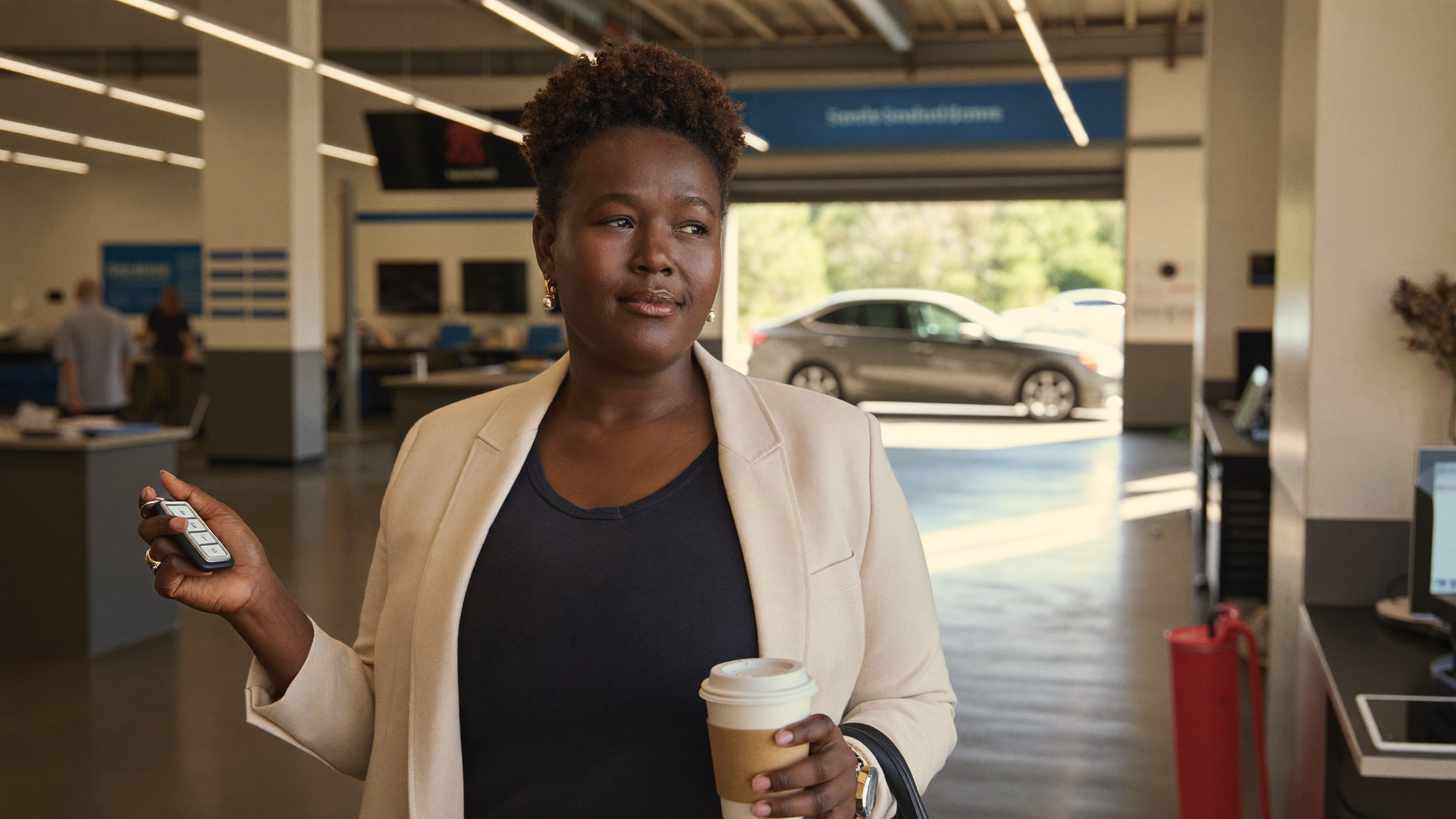 Woman with key fob smiling in dealership service lane