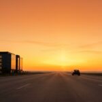 Car driving toward a bright sunrise horizon on an open highway